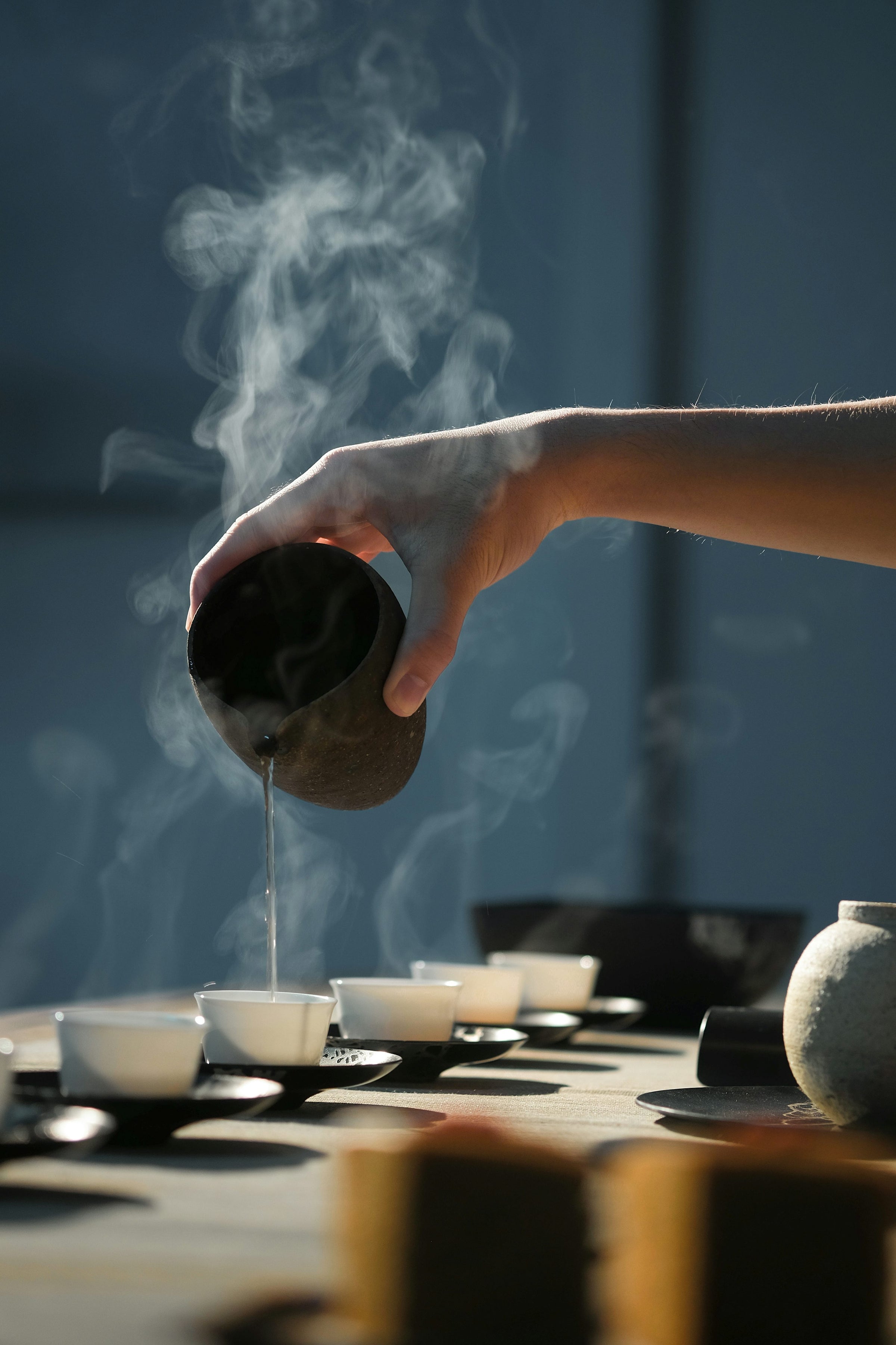 A handcrafted tea setting and steaming cup in warm daylight